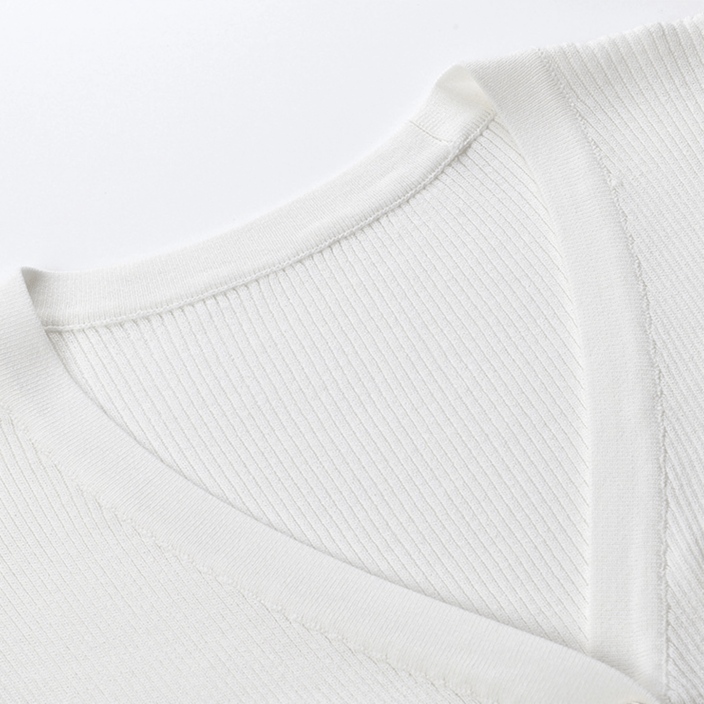 Close-up of a white sweater with ribbed texture on a light gray background