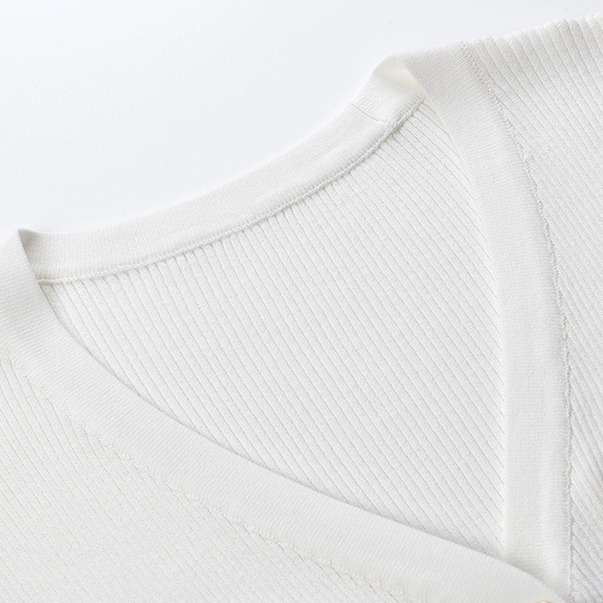 Close-up of a white sweater with ribbed texture on a light gray background