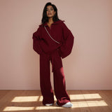 Person wearing a burgundy outfit with a matching jacket and pants on a gray background