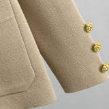 Close-up of a beige textured fabric with gold buttons on a gray background