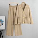Beige outfit with gold buttons on a hanger against a gray background