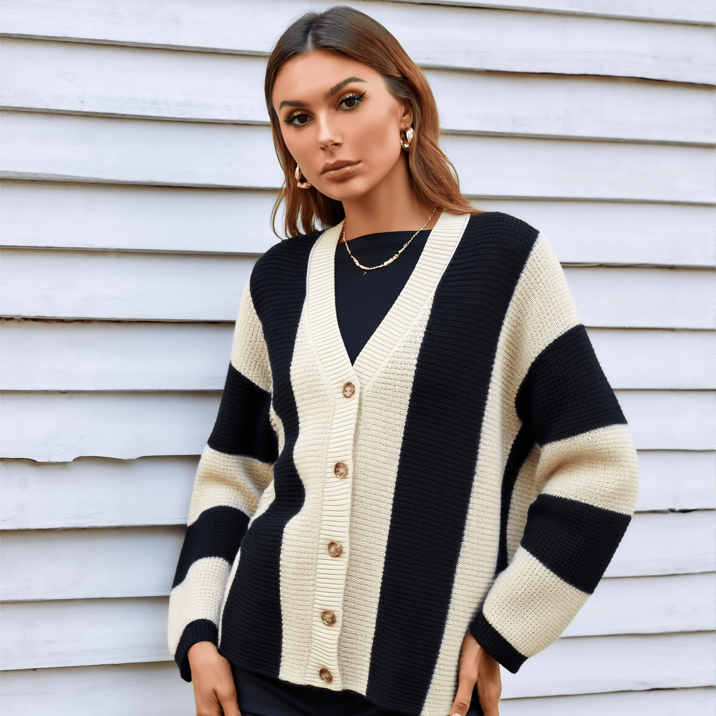 Woman wearing a black and white striped cardigan against a white wall.