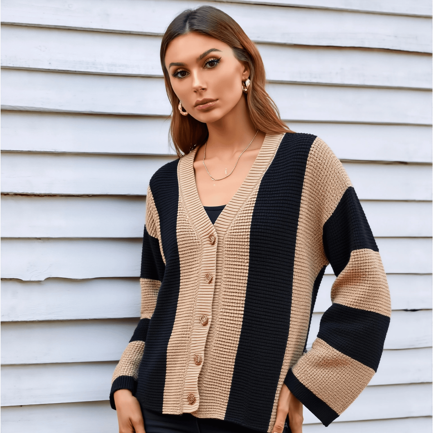 Woman wearing a beige and black striped cardigan against a light-colored wall.