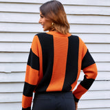 Person wearing an orange and black striped sweater against a white wall.