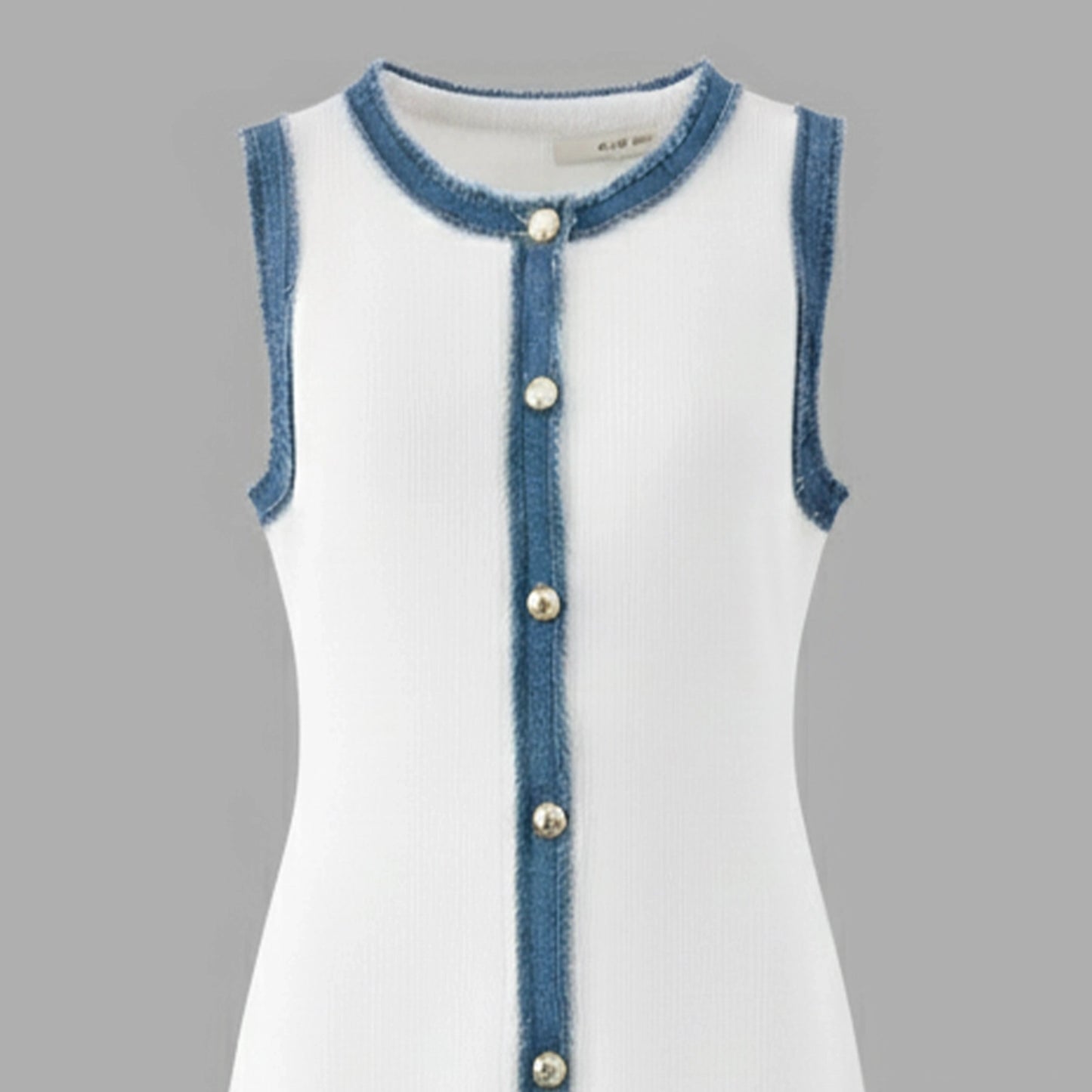 White dress with blue denim trim and buttons on a gray background