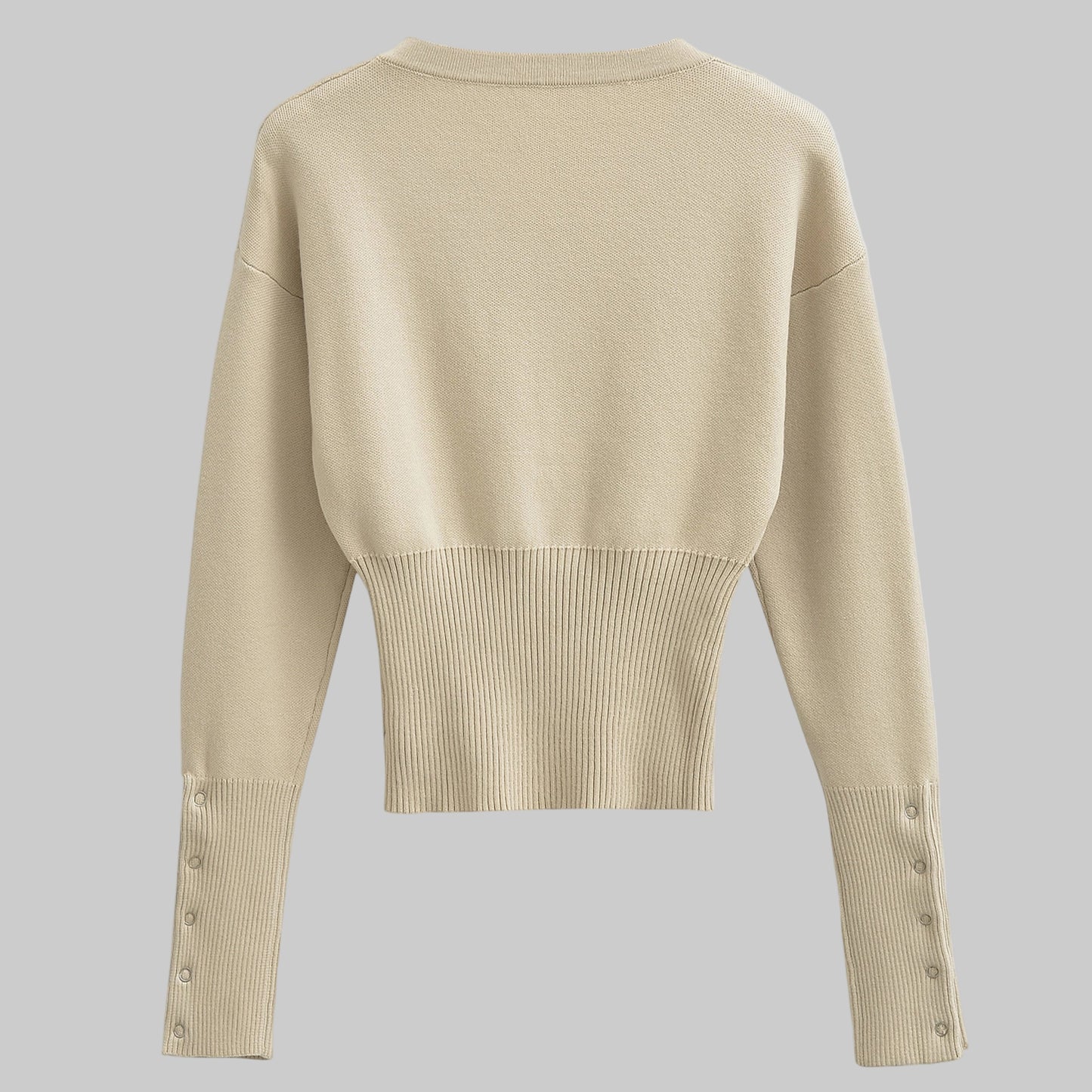 Beige sweater with button details on a gray background