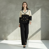 Woman wearing a black and white suit with gold buttons on a gray background