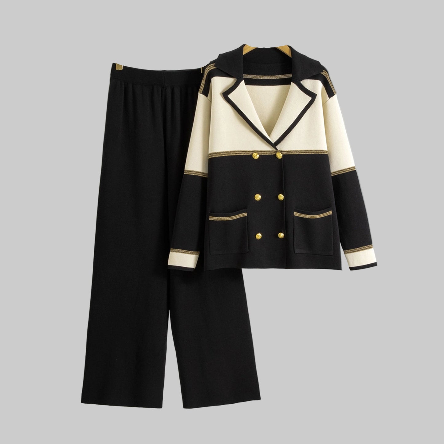Black and white outfit with jacket and pants on hangers against a gray background