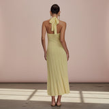 Woman wearing a yellow halter neck dress with a bow detail on a plain background