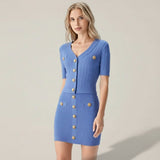 Woman wearing a blue dress with gold buttons on a plain background