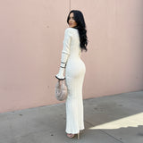 Woman wearing a white dress with black accents against a plain background