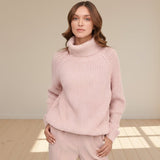 Woman wearing a pink turtleneck sweater on a gray background