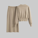 Beige sweater and skirt set on hangers against a gray background