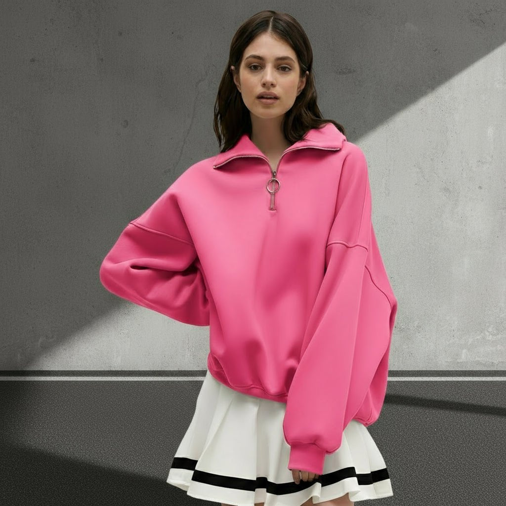 Woman wearing a pink oversized sweatshirt with a white skirt on a gray background