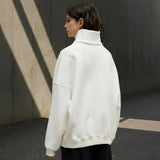 Person wearing a white sweater on a gray background