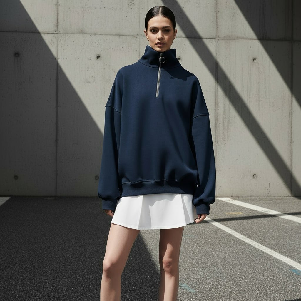 Person wearing a navy blue high-neck sweatshirt on a gray background