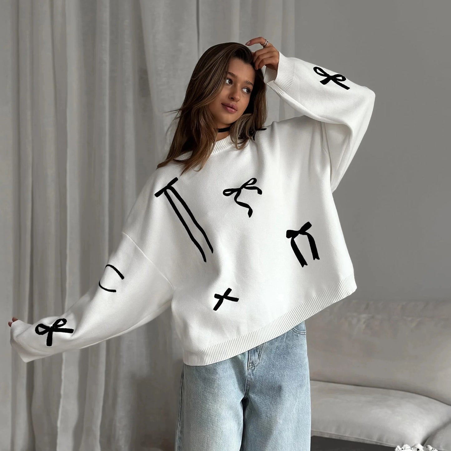 Person wearing a white sweater with black patterns against a neutral background