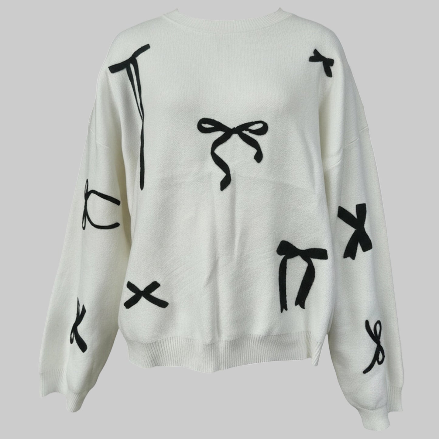 White sweater with black abstract designs on a light gray background
