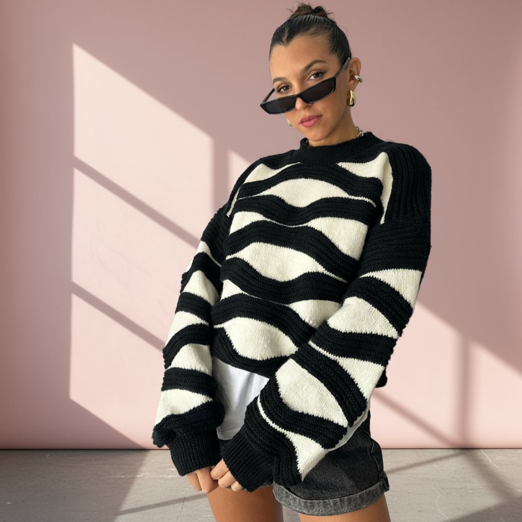 Woman wearing a black and white striped sweater against a pink wall.