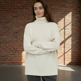 Woman wearing a cream turtleneck sweater against a plain background