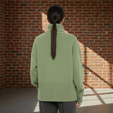 Person wearing a green sweater from behind on a gray background