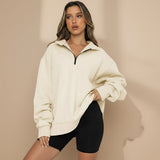 Woman wearing a beige oversized hoodie and black shorts on a gray background