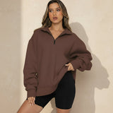 Woman wearing a brown oversized sweatshirt and black shorts on a gray background