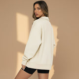 Woman wearing a beige oversized hoodie on a gray background