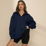 Woman wearing a navy blue oversized sweatshirt and black shorts on a gray background
