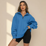 Woman wearing a blue sweatshirt and black shorts on a gray background