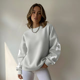 Woman wearing a light gray sweatshirt with a brand logo against a neutral background
