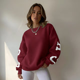Woman wearing a maroon sweatshirt with white lettering against a neutral background