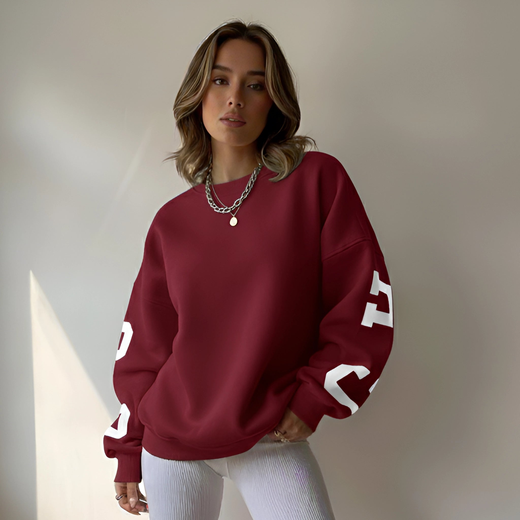 Woman wearing a maroon sweatshirt with white lettering against a neutral background