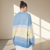 Person wearing a colorful sweater with patterns and bows in a bright room.