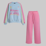 Light blue sweatshirt with pink and yellow accents and pink pants on a gray background