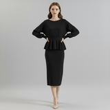 Woman wearing a black peplum top and pencil skirt on a gray background