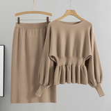 Beige sweater and skirt set on hangers against a gray background