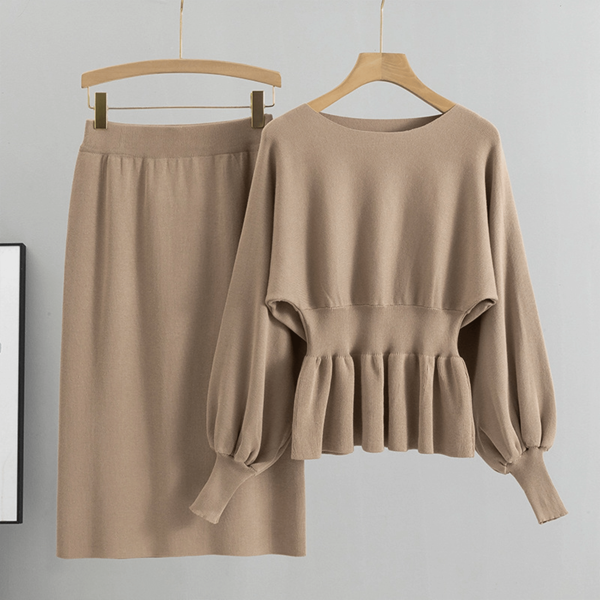 Beige sweater and skirt set on hangers against a gray background