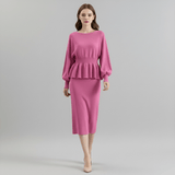 Woman wearing a pink dress with a peplum top on a gray background