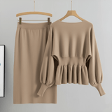 Beige long-sleeve top and skirt set on hangers against a gray background