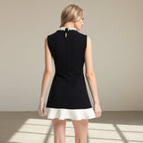 Woman wearing a black dress with white trim on a gray background