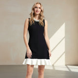 Woman wearing a black dress with a white hem on a gray background