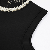 Black sleeveless top with pearl embellishments on a white background