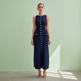 Woman wearing a navy blue dress with buttons on a gray background