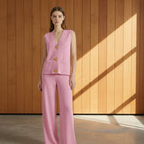 Woman wearing a pink suit with gold buttons on a gray background