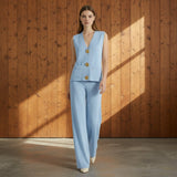 Woman wearing a light blue suit with gold buttons on a gray background