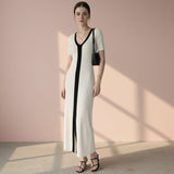 Woman wearing a long dress with a black side panel on a gray background