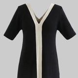 Black dress with white trim on a white background