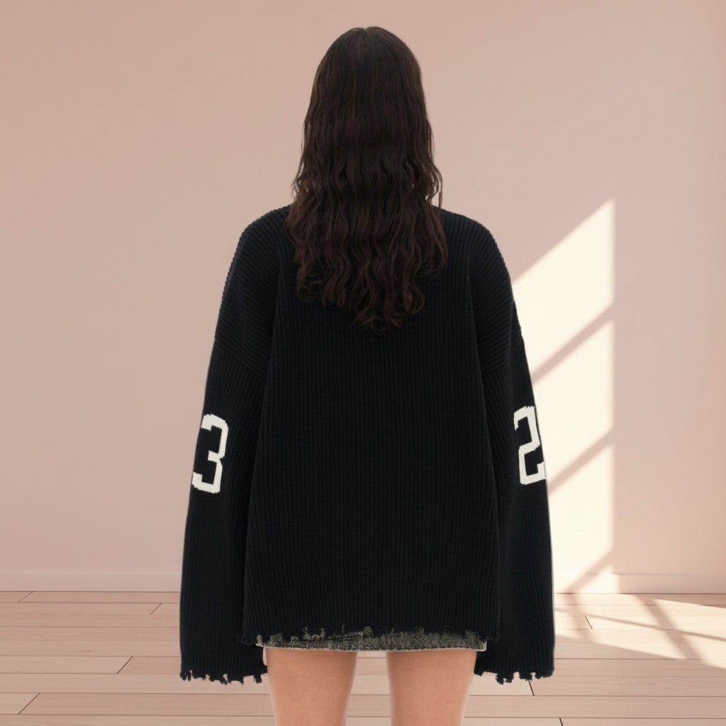 Person wearing a black oversized sweater with numbers on a plain background