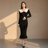 Woman wearing a black dress with white collar and buttons on a gray background